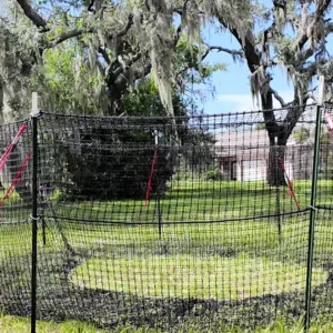 16:9 landscape close view of The P.I.G. Hog Trap™ at ground level with a home in the background, showcasing a complete sounder removal solution designed to help protect homes, property, and surrounding land from feral hog damage.