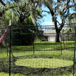 16:9 landscape view of The P.I.G. Hog Trap™ with natural colors and a home in the background, showcasing a feral hog control solution designed to help protect residential property through complete sounder removal.