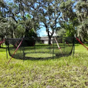 1:1 square full view of The P.I.G. Hog Trap™ at ground level with a home in the background, showcasing a complete sounder removal system designed to help protect homes, family property, and surrounding land from destructive feral hog activity.
