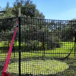 9:16 vertical close-up view of The P.I.G. Hog Trap™ showing the support pole, bracket assembly, and net attachment strap at ground level, highlighting a durable wild hog trapping system designed for complete sounder removal and effective feral hog control.